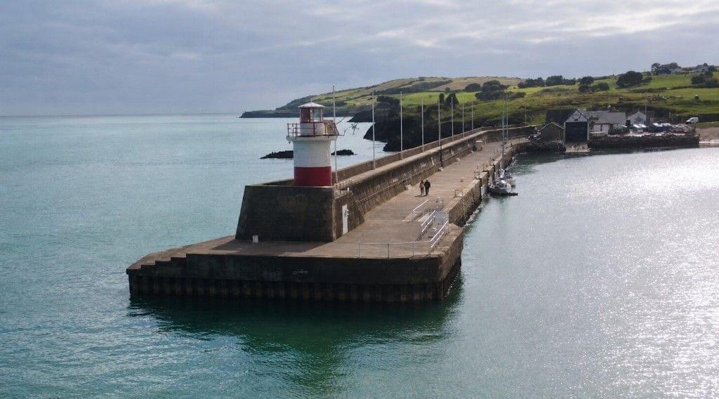 Wicklow's East Pier light: a short white tower with a red base on a stepped pierhead.